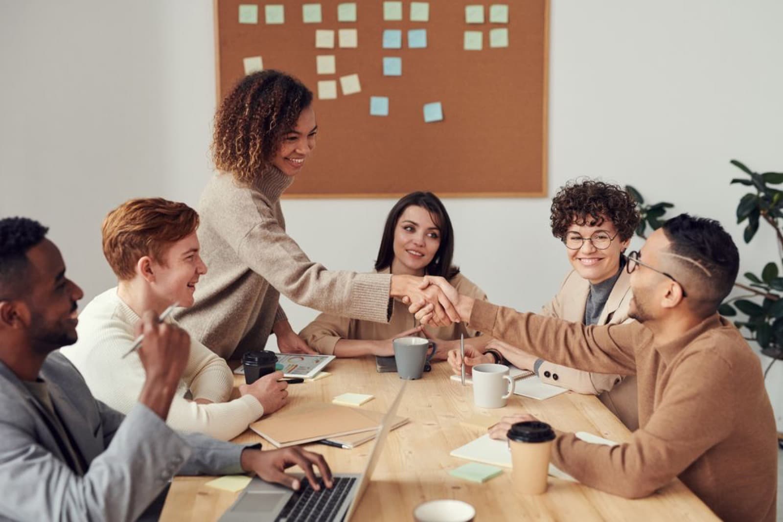 Two business people shaking hands across a table during a meeting