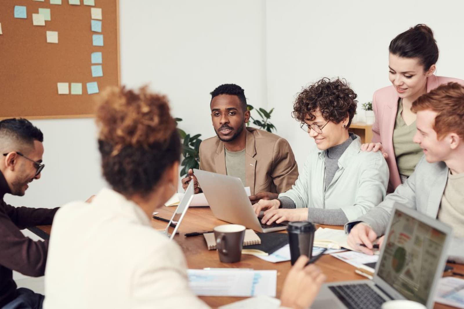 A team of colleagues collaborating around laptops in a meeting room